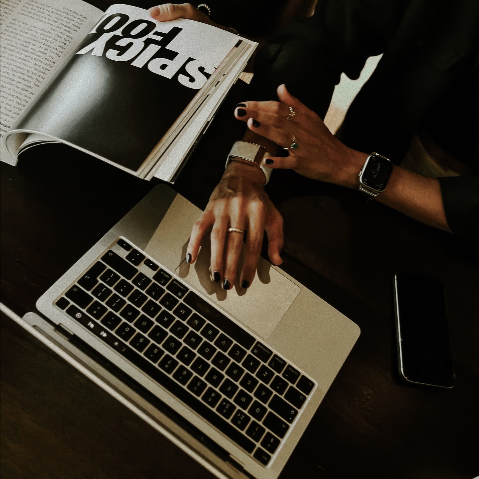 Hands on a laptop beside an open magazine spread in the june19 studio