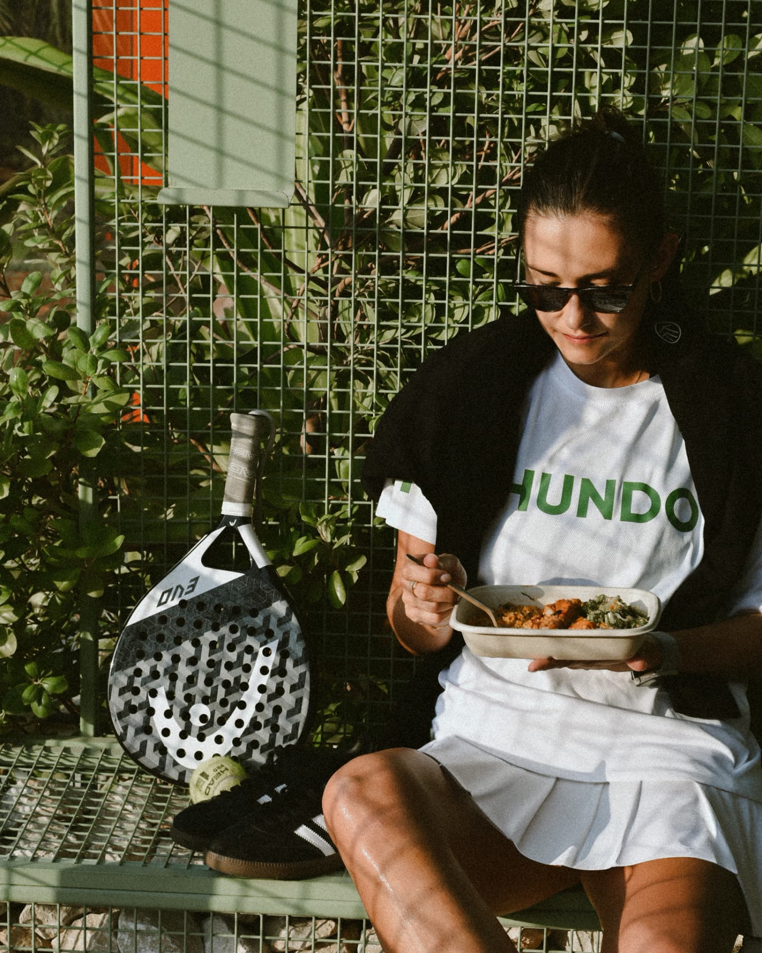HUNDO padel player with meal courtside
